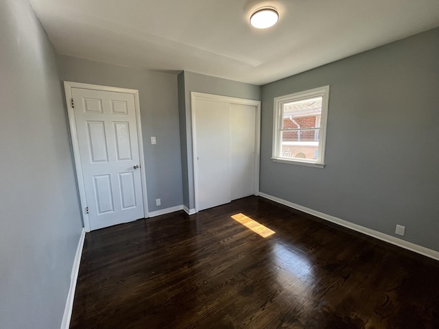 unfurnished bedroom with dark hardwood / wood-style floors and a closet