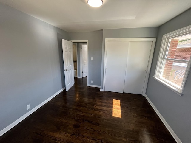 unfurnished bedroom with dark wood-type flooring and a closet