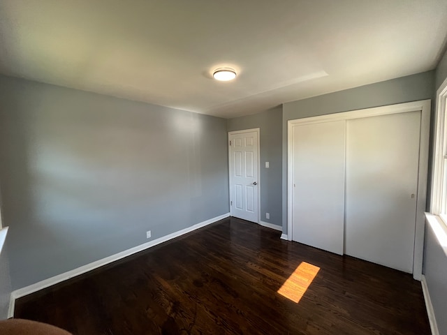 unfurnished bedroom with a closet and dark wood-type flooring