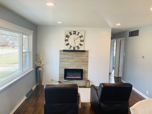 living room featuring a tile fireplace and dark hardwood / wood-style floors