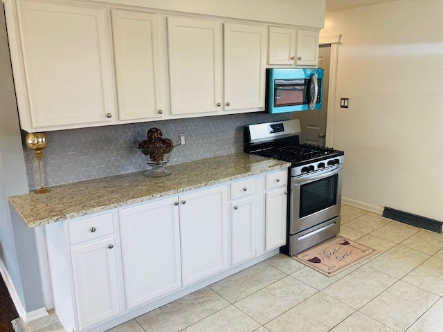 kitchen featuring tasteful backsplash, light stone countertops, stainless steel range with gas stovetop, and white cabinets