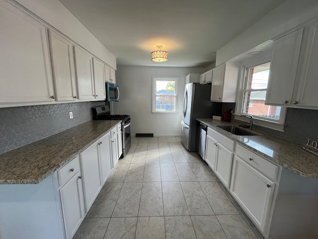 kitchen with appliances with stainless steel finishes, sink, a wealth of natural light, and white cabinetry