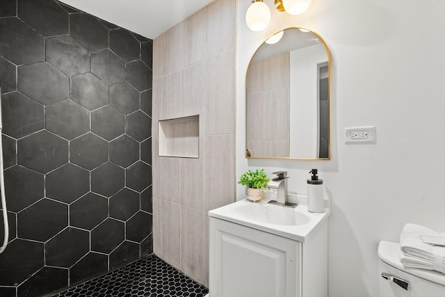 bathroom featuring tiled shower, vanity, and toilet