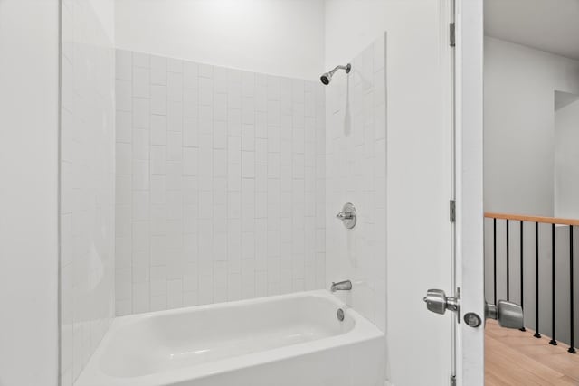 bathroom with hardwood / wood-style flooring and tiled shower / bath