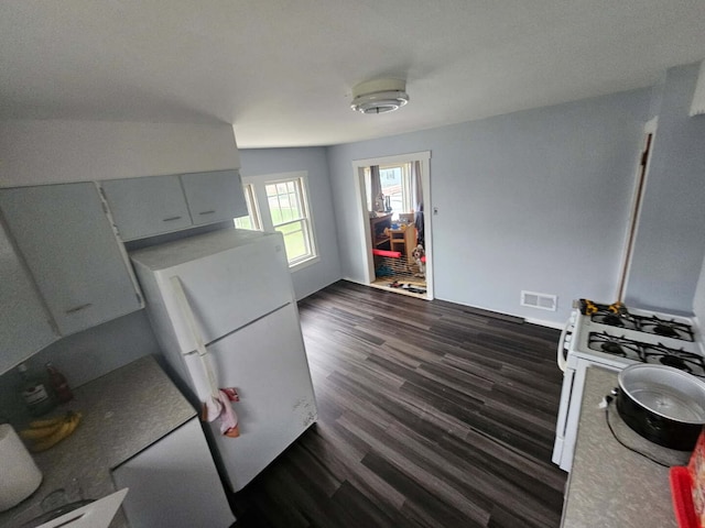 kitchen featuring dark wood finished floors, visible vents, and white appliances