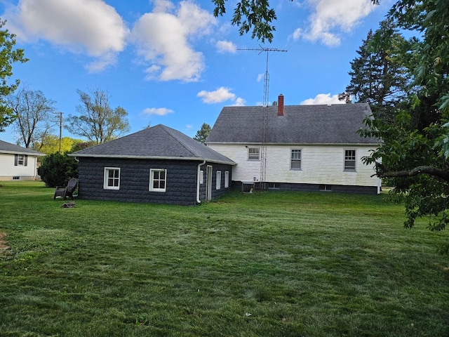 rear view of house featuring a yard and a chimney