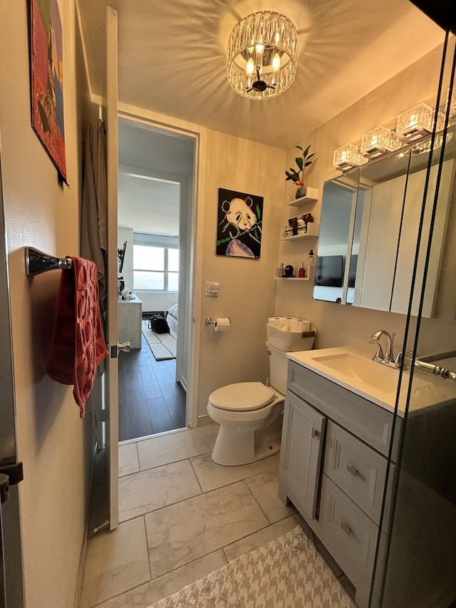 bathroom with hardwood / wood-style floors, a chandelier, vanity, and toilet