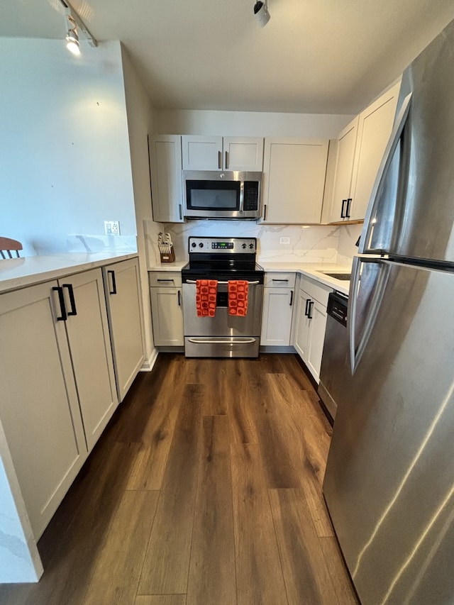 kitchen with appliances with stainless steel finishes, decorative backsplash, white cabinetry, and dark hardwood / wood-style flooring