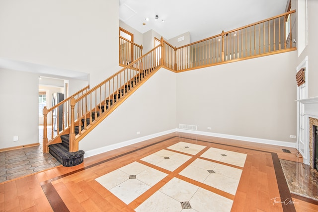 interior space featuring a fireplace, a towering ceiling, and hardwood / wood-style flooring