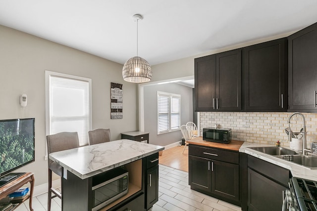 kitchen featuring pendant lighting, sink, backsplash, stainless steel appliances, and a breakfast bar area