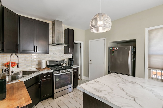 kitchen featuring wall chimney exhaust hood, an inviting chandelier, decorative light fixtures, sink, and stainless steel appliances