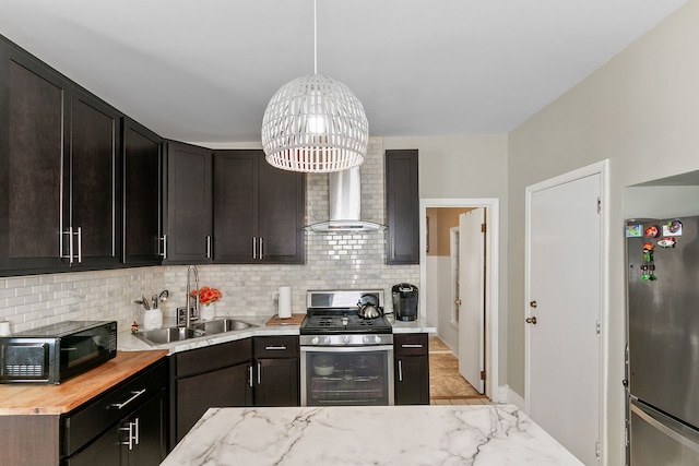 kitchen featuring wall chimney exhaust hood, pendant lighting, tasteful backsplash, sink, and stainless steel appliances