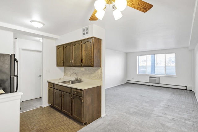 kitchen with dark brown cabinetry, a baseboard radiator, freestanding refrigerator, and a sink