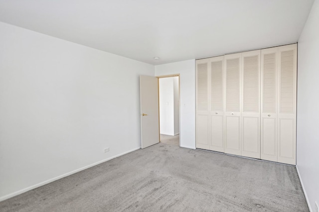 unfurnished bedroom with baseboards, carpet floors, and a closet