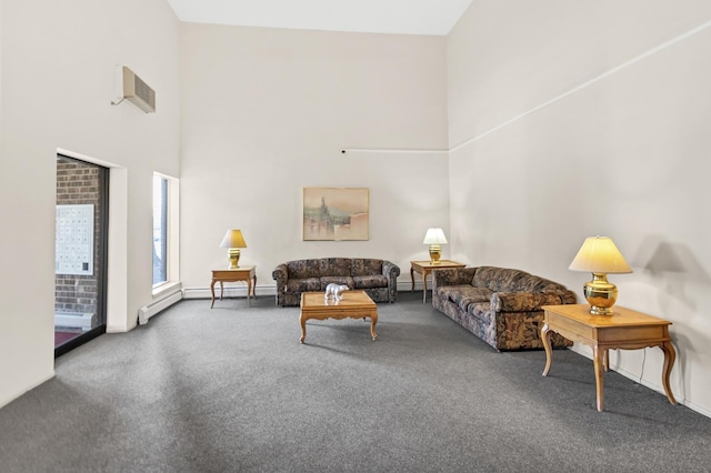 carpeted living area featuring a high ceiling and baseboard heating