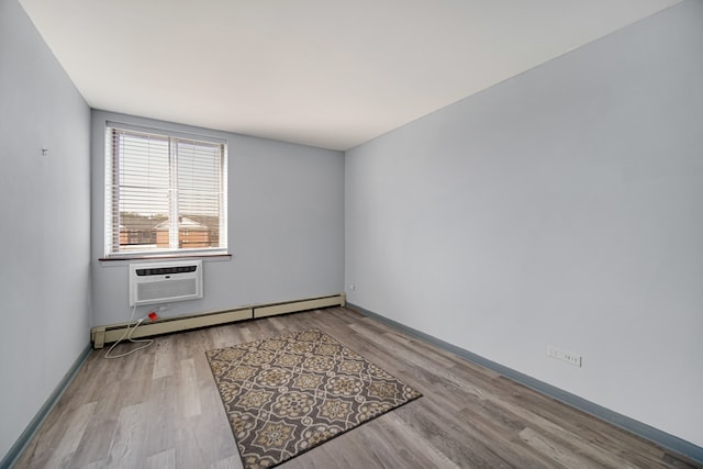 unfurnished room featuring an AC wall unit, light wood-type flooring, and baseboard heating