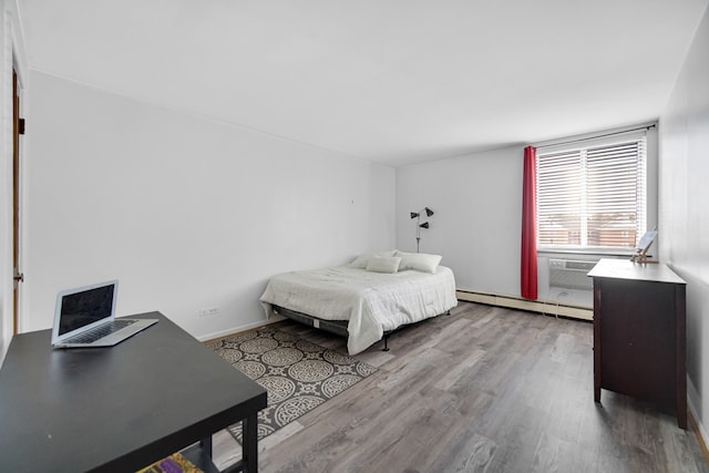 bedroom featuring cooling unit, light hardwood / wood-style floors, and a baseboard heating unit