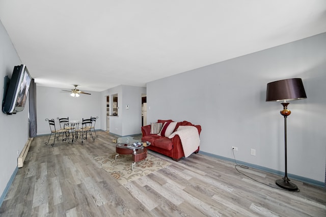 living room with baseboard heating, ceiling fan, and light hardwood / wood-style flooring