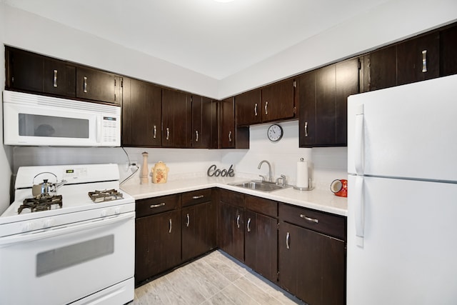 kitchen featuring dark brown cabinetry, sink, and white appliances