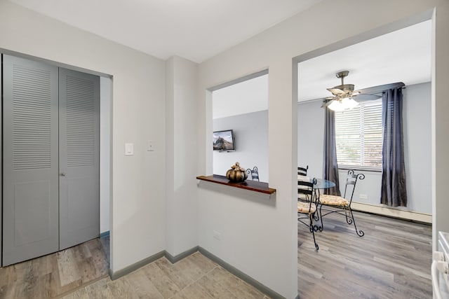 office area with light wood-type flooring, baseboard heating, and ceiling fan