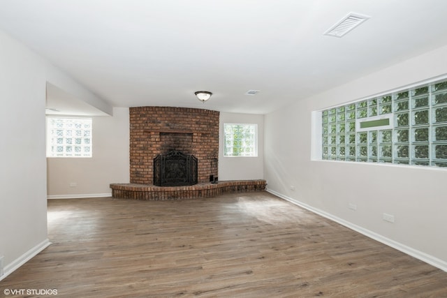 unfurnished living room featuring a brick fireplace and hardwood / wood-style flooring