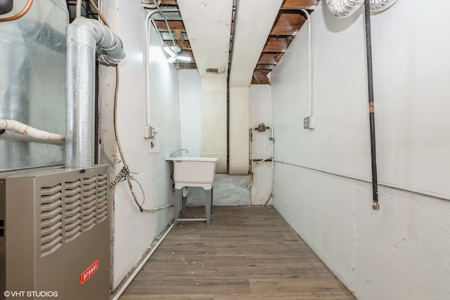 basement with wood-type flooring, sink, and heating unit