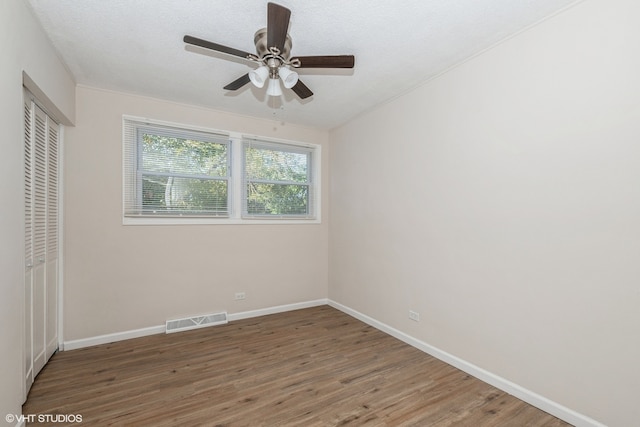 unfurnished bedroom featuring ceiling fan, a textured ceiling, a closet, and dark hardwood / wood-style floors