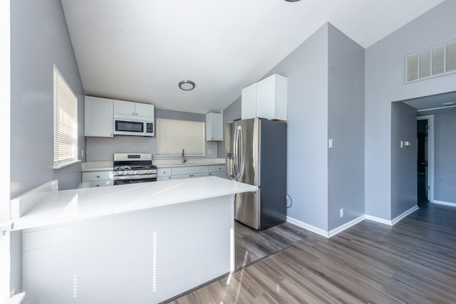 kitchen featuring stainless steel appliances, white cabinets, kitchen peninsula, and dark wood-type flooring