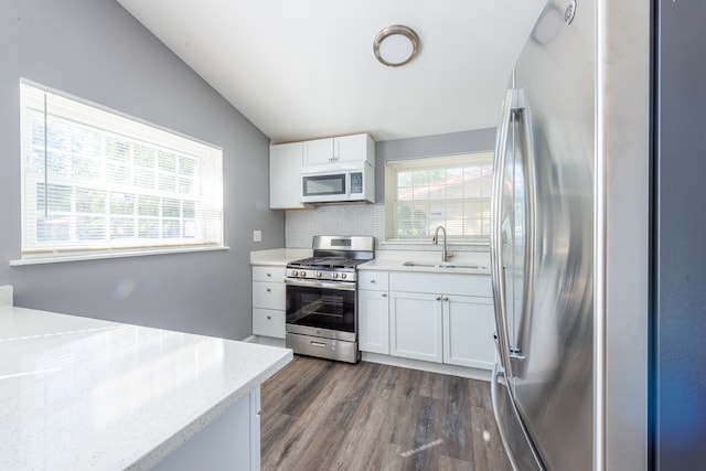 kitchen with vaulted ceiling, dark hardwood / wood-style floors, stainless steel appliances, and white cabinets