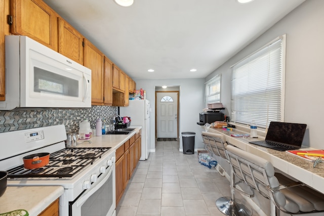 kitchen featuring backsplash, white appliances, and light tile patterned floors