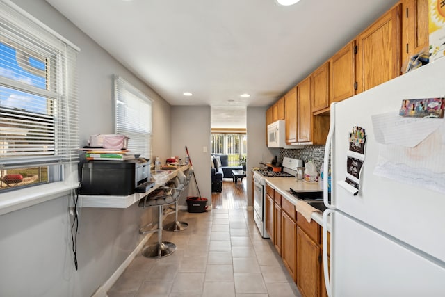 kitchen with white appliances, light tile patterned floors, and backsplash