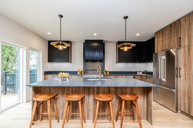 2715 Reese Ave, Evanston, IL 60201 - kitchen with high end fridge, a sink, light wood-type flooring, a breakfast bar, and a kitchen island with sink