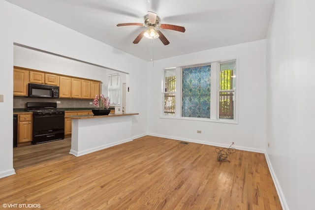 kitchen featuring kitchen peninsula, black appliances, light wood-type flooring, and ceiling fan