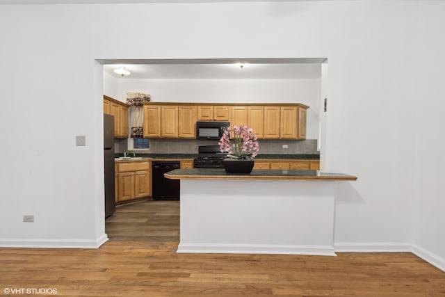 kitchen featuring kitchen peninsula, black appliances, backsplash, and dark hardwood / wood-style flooring