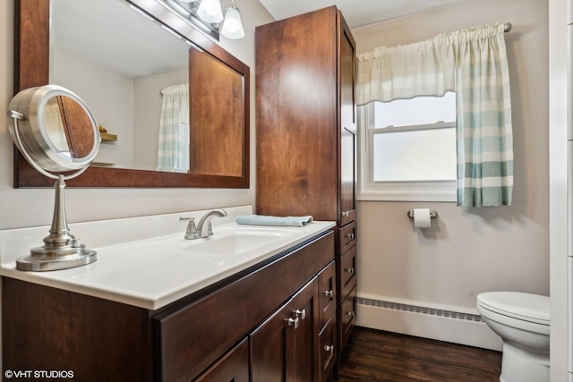 bathroom featuring baseboards, toilet, a baseboard radiator, vanity, and wood finished floors