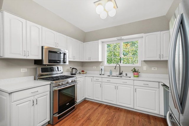 kitchen featuring light hardwood / wood-style floors, appliances with stainless steel finishes, sink, and white cabinets