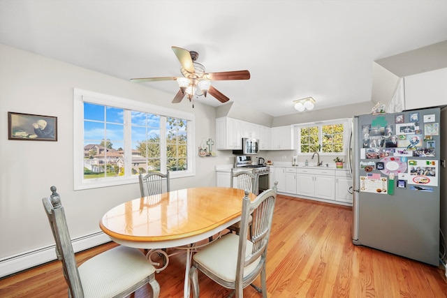 dining space featuring ceiling fan, sink, light wood-type flooring, and a baseboard heating unit