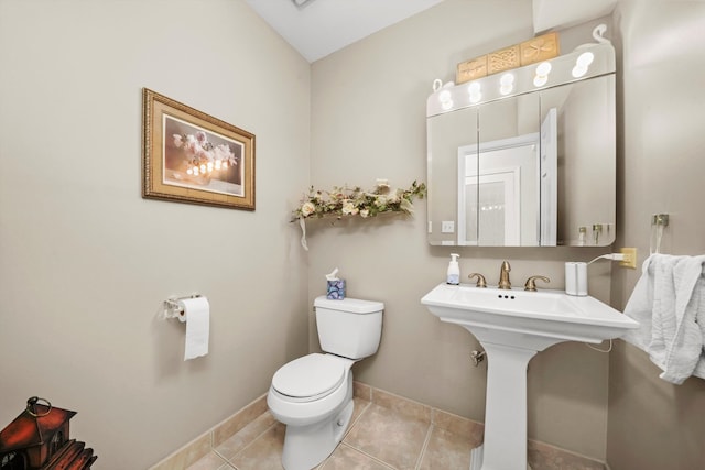 bathroom with toilet, sink, and tile patterned flooring