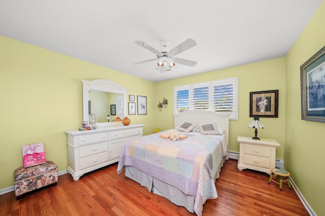 bedroom featuring hardwood / wood-style floors, baseboard heating, and ceiling fan