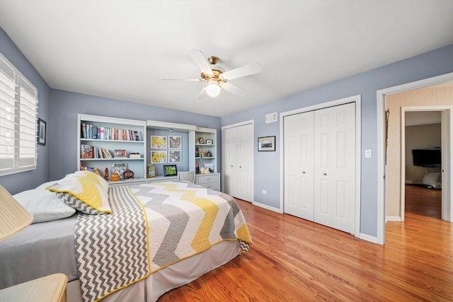 bedroom with multiple closets, light hardwood / wood-style floors, and ceiling fan