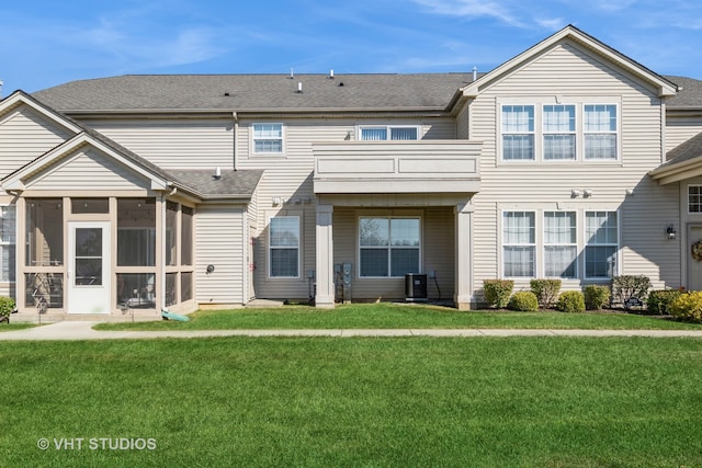 rear view of property with a sunroom, central AC, a balcony, and a lawn