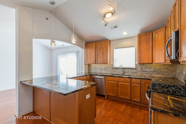 kitchen featuring pendant lighting, dark wood-type flooring, sink, stainless steel appliances, and kitchen peninsula