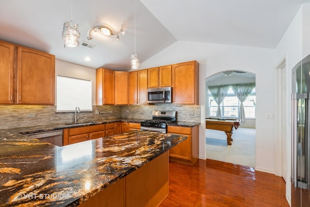 kitchen featuring lofted ceiling, decorative backsplash, stainless steel appliances, sink, and pendant lighting