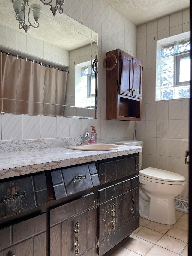 bathroom with toilet, tile patterned flooring, vanity, and a wealth of natural light