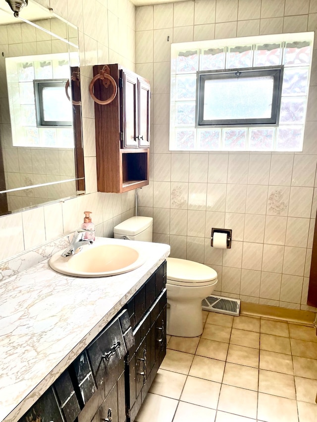 bathroom featuring vanity, toilet, a healthy amount of sunlight, and tile patterned flooring