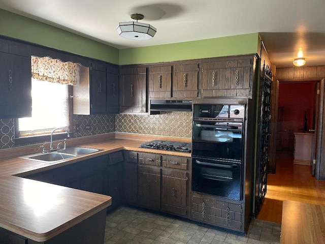 kitchen with tasteful backsplash, black appliances, sink, kitchen peninsula, and dark brown cabinetry