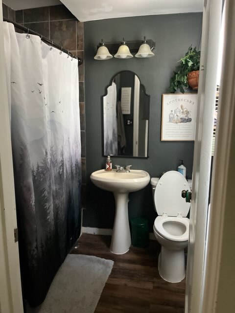 bathroom featuring hardwood / wood-style flooring, toilet, and walk in shower