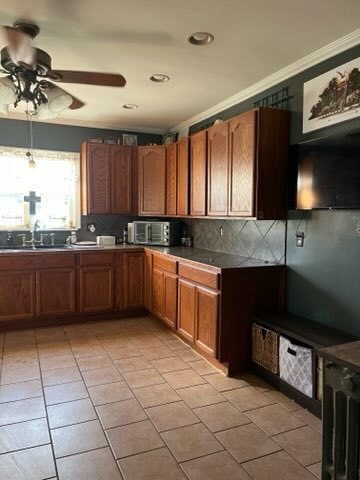 kitchen with decorative backsplash, light tile patterned floors, ceiling fan, ornamental molding, and sink