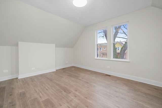 bonus room with light wood-type flooring and vaulted ceiling