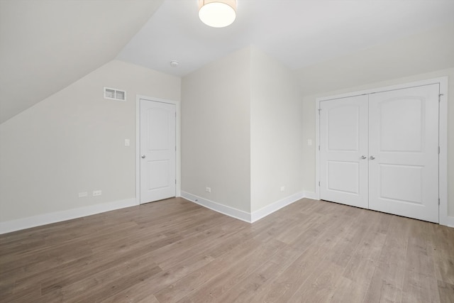 additional living space with light hardwood / wood-style floors and vaulted ceiling